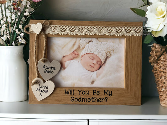 Image shows vintage brown will you be my godmother photo frame, consists of two hanging hearts with god mothers and god child's name, as well as a smaller dotted heart above, cream lace runs along the top.