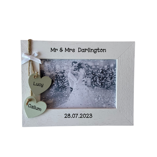 Image shows mr and mrs wedding photo frame, including two hanging hearts with bride and groom names, also with a small white bow attached above, bling can be added.