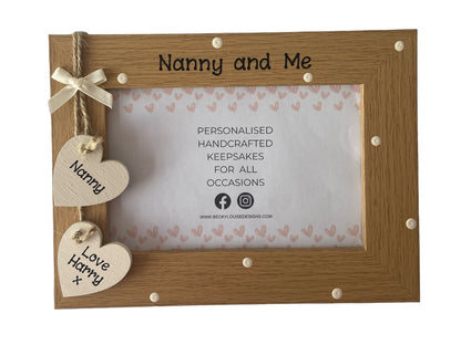 Image shows nanny and me vintage photo frame, decorated with cream polka dots and two cream hanging wooden hearts for names, with a cream bow above.