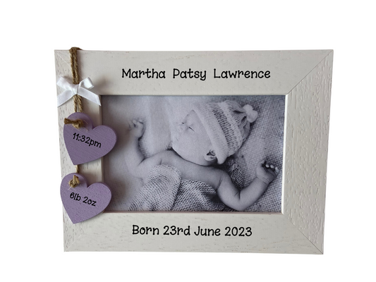 Image shows new born baby photo frame, consists of two hanging wooden hearts for weight and time of birth, attached is a small white bow. Gems can be added.
