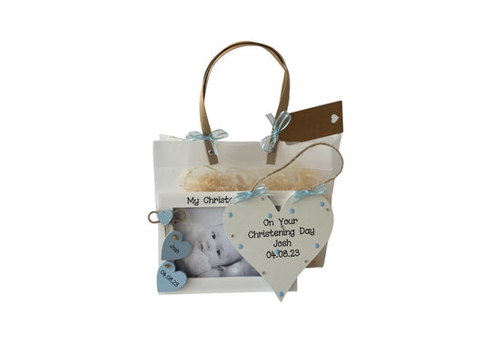 Image shows pairing photo frame and plaque included in this christening gift set, plaque is decorated with polka dots, bling and ribbon, photo frame consists of two wooden hanging hearts with name and date on, above sits a smaller dotted heart. Gift wrap and photo included.