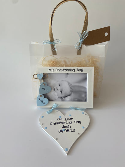 Image shows pairing photo frame and plaque for christening day, photo frame consists of two hanging hearts with name and date also a small heart with polka dots is placed above, plaque is decorated with polka dots, gems and ribbon. Gift wrap and photo of your choice included.