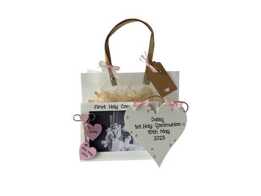 Image shows pairing photo frame and plaque for a first holy communion, plaque is decorated with bling, polka dots and ribbon, photo frame has two wooden hanging hearts so a name and date can be included, above sits a small dotted heart. Gift wrap and photo included.
