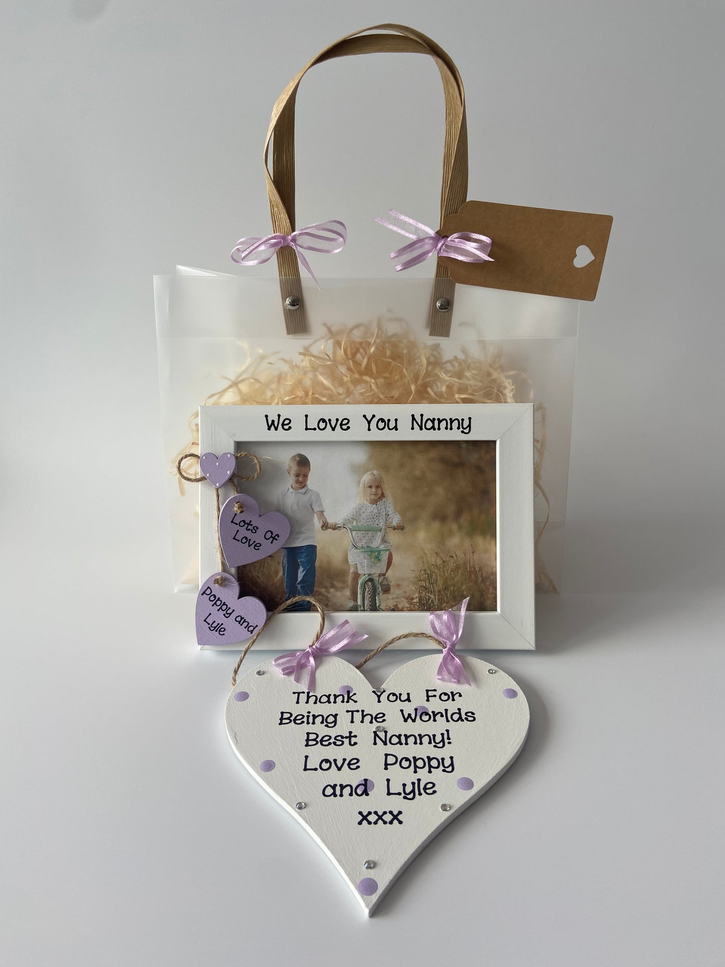 Image shows gift set including frame and plaque for a nanny, plaque decorated with polka dots, gems and ribbon, Frame includes two hearts with text and names of ur choice. Includes ur own photo and gift wrap.