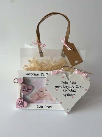 Image shows photo frame and plaque included in this new born keep sake set, plaque decorated with polka dots, gems and ribbon, photo frame included two hanging hearts with baby's date of birth, weight and time of birth, also a small heart sat above with white polka dots. Includes gift wrap and photo of your choice.