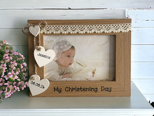 Image shows vintage christening day photo frame, consists of two hanging hearts with name and date, as well as a smaller dotted heart above, cream lace runs along the top.