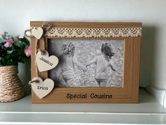 Image shows vintage cousins photo frame, consists of two cream hanging hearts with cousins names as well as a small heart above, cream lace runs above the top