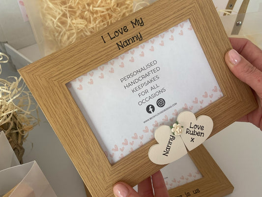 Image shows vintage nanny photo frame, decorated with two cream hearts with names and a heart between.