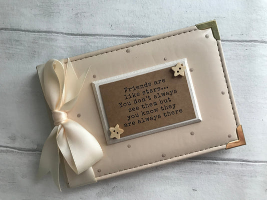Image shows natural photo album with friends quote, decorated with beige polka dots, cream bow, cream plaque and 2 stars either corner of the plaque.