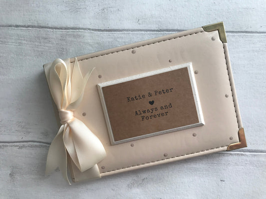 Image shows our couple photo album, decorated with beige polka dots, cream ribbon and cream plaque with text and names written on.