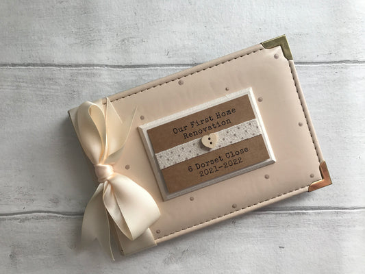 Image shows 6x4 photo album for house renovations, decorated with beige dots, cream ribbon and cream plaque with dotted ribbon and small wooden heart, address and date added to plaque