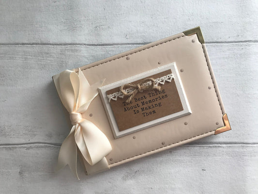 Image shows photo album designed for memories, decorated with beige polka dots, cream ribbon, and cream plaque with patterned ribbon and natural bow, also with the quote printed onto plaque.