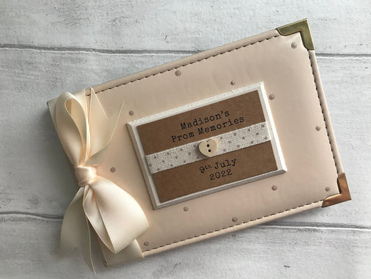 Image of photo album for prom memories, decorated with beige polka dots, cream ribbon, and cream plaque with dotted ribbed and small wooden heart, text also printed onto plaque.