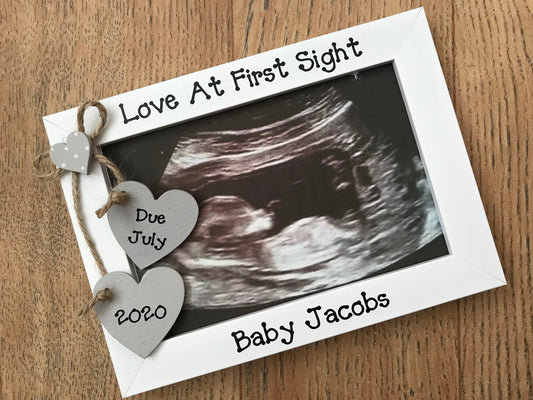 Image shows baby scan photo frame, with two hanging hearts including due date and a small white dotted heart sits above.
