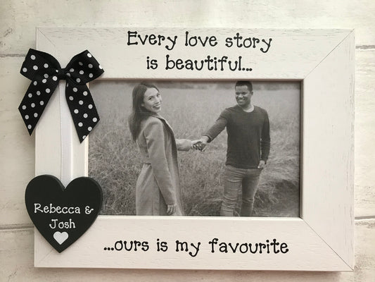 Image shows wooden couple photo frame, attached is a wooden heart with couples names, attached to a dotted bow with a white piece of ribbon.