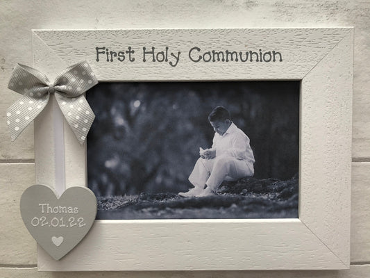 Image shows first holy communion wooden frame, consists of wooden heart with name and date on, attached to white ribbon and dotted bow.