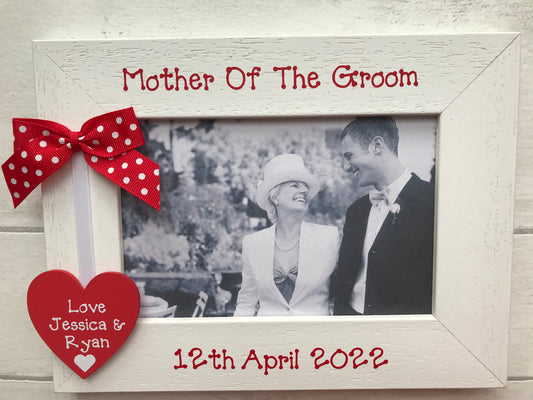 Image shows a mother of the groom photo frame, consisting of a wooden heart with bride and grooms names attached to white ribbon and dotted bow.