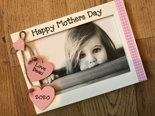 Image shows wooden gingham photo frame for mothers day gift, consists of two hanging hearts with child's name and year, down the side runs gingham ribbon.