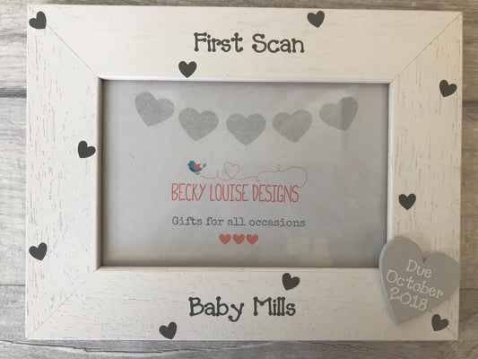 Image shows wooden baby scan photo frame, with small grey heart down the side with due date and small hearts around the heart.