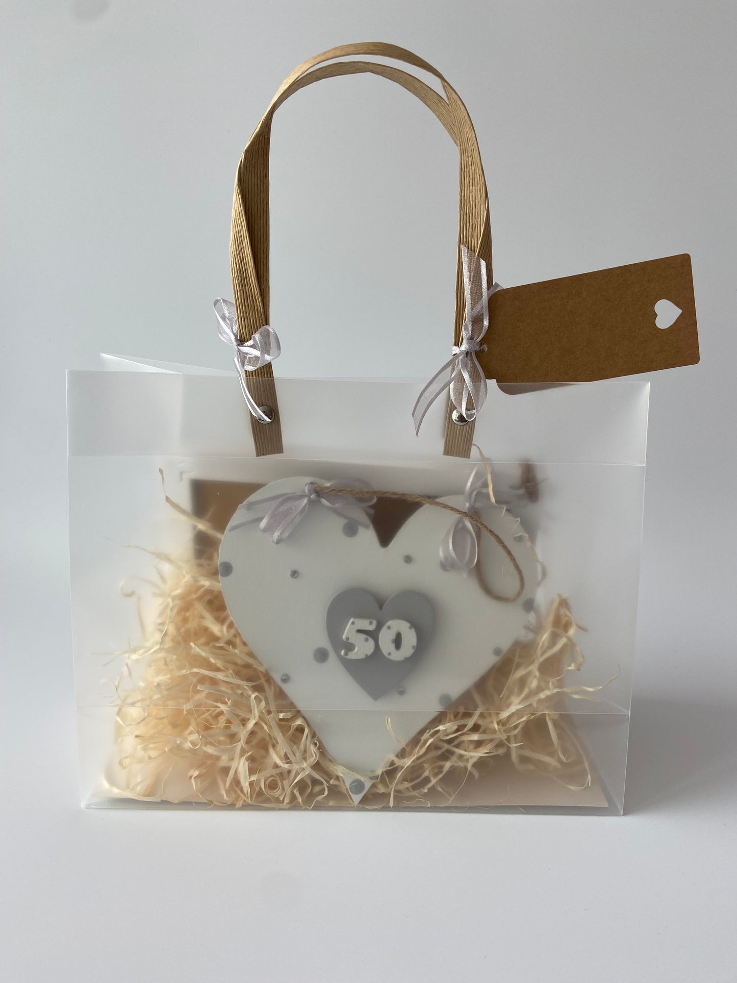 Image shows a 50th birthday plaque decorated with polka dots, gems and ribbon